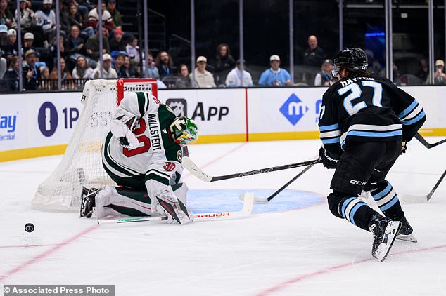 Minnesota Wild goaltender Jesper Wallstedt (30) makes the behind the back save on a shot from Utah Mammoth center Barrett Hayton (27) during the second period of an NHL hockey game Tuesday, Oct. 27, 2026, in Salt Lake City. (AP Photo/Tyler Tate)
