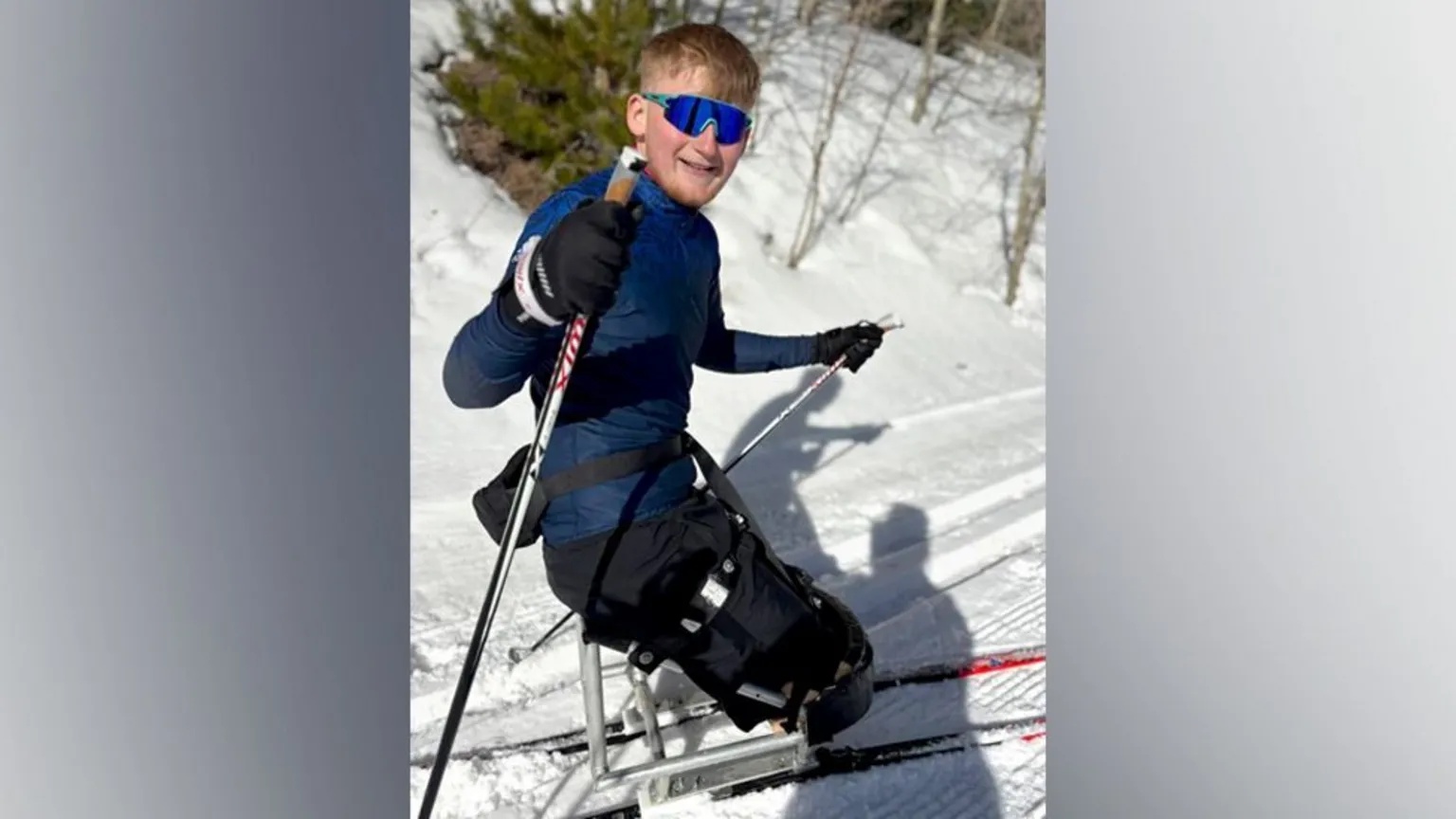 Adam Golebiewski Adam Golebiewski, a young man who has lost both legs, on skis in snow, he is smiling at the camera.