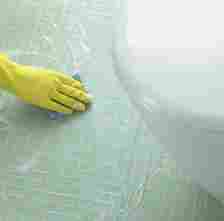 Hand in a Rubber Glove Cleaning a Tiled Floor in a Bathroom