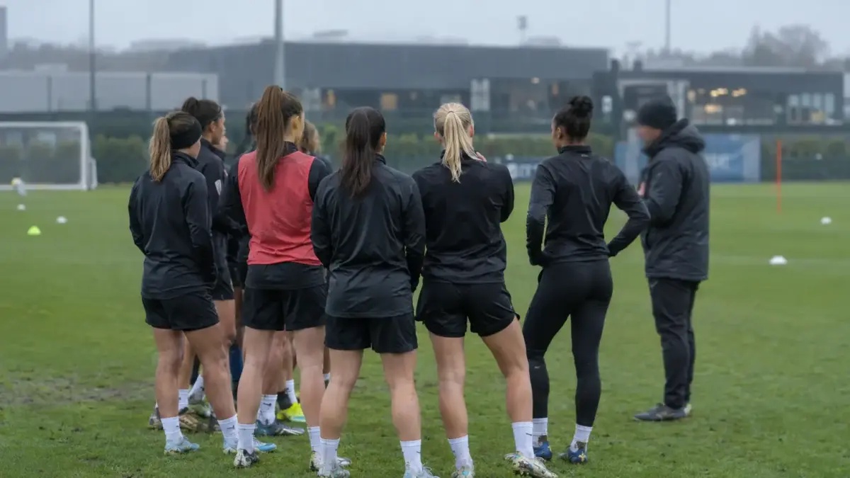 Women footballers regroup during a training session at a Manchester practice ground