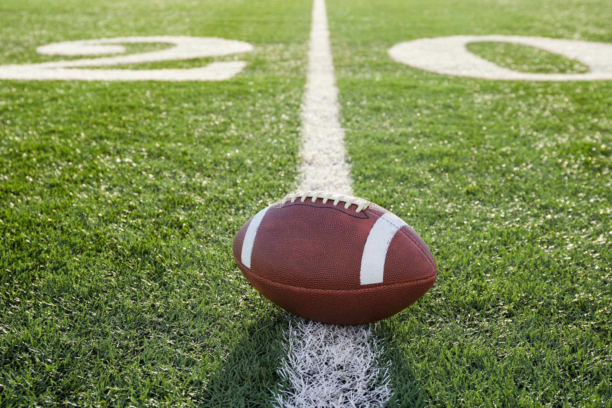 A football sitting on the yard line of a football field.