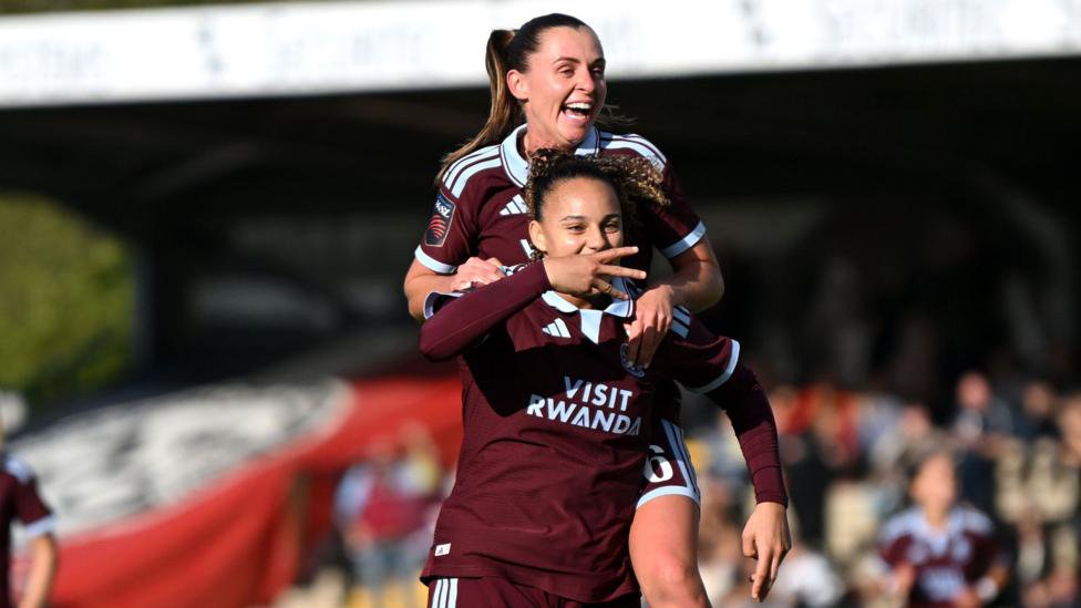 Chasity Grant celebrates her goal for Aston Villa by holding out three fingers sideways while team-mate Noelle Maritz jumps on her back
