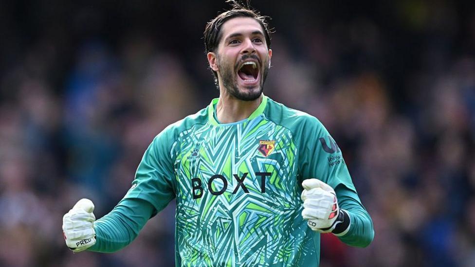 Watford goalkeeper Federico Ravaglia, in green top, clenches both fists and shouts to celebrate Watford's goal against Charlton Athletic.