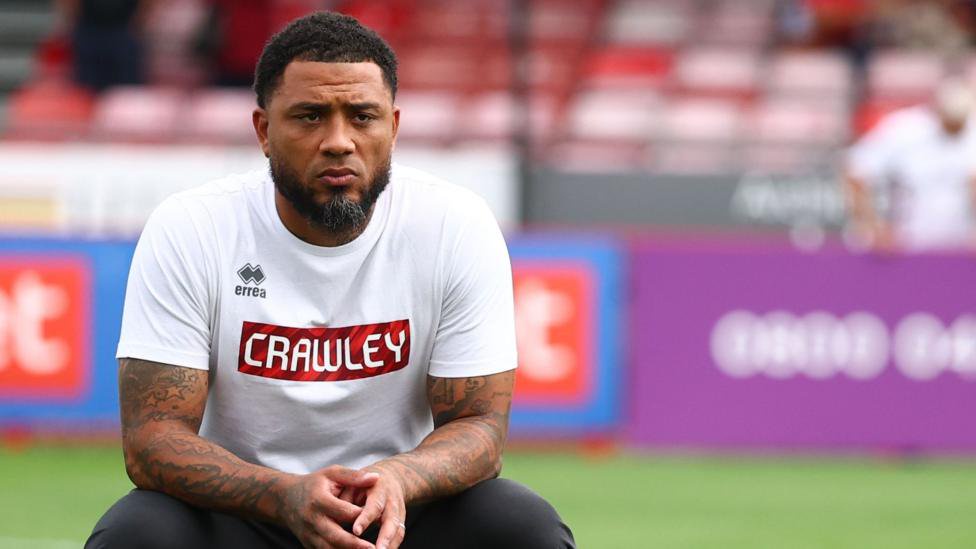 Colin Kazim-Richards looking pensive, wearing a white top with Crawley written on it