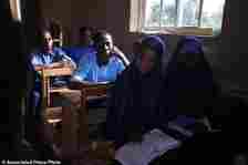 Students of Excellent Moral School attend a lesson in a dimly lit classroom in Ibadan, Nigeria, Tuesday, May 28, 2024. Schools like Excellent Moral operate in darkness due to zero grid access, depriving students of essential tools like computers. (AP Photo/Sunday Alamba)