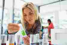 Woman examining skincare product in drugstore