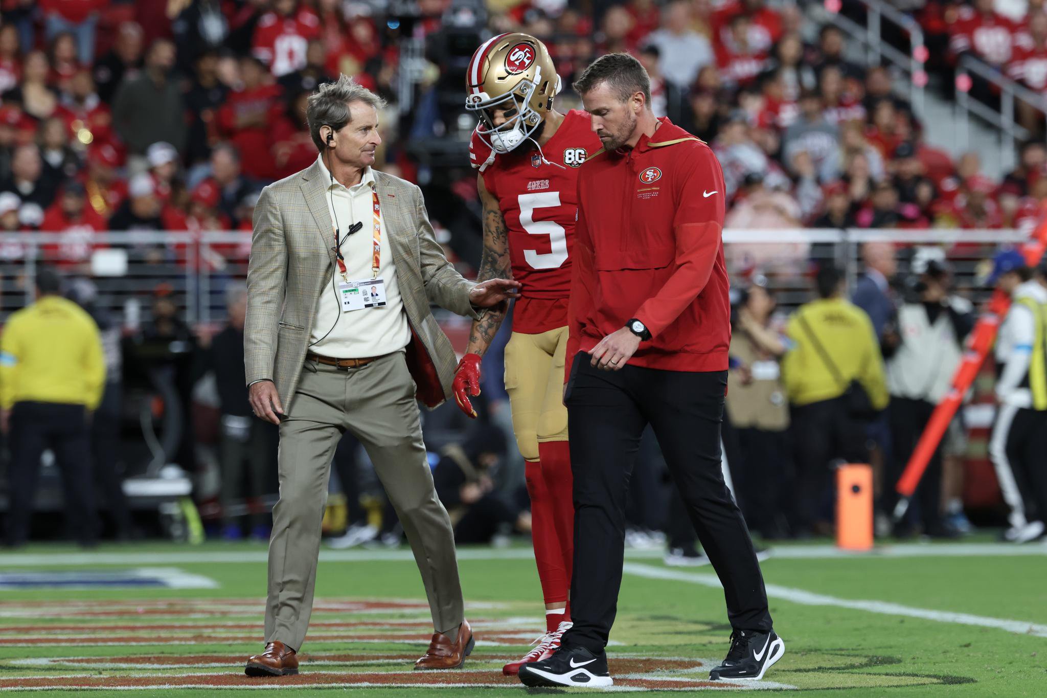 San Francisco 49ers quarterback Trey Lance talks with general manager John Lynch and head coach Kyle Shanahan on the field.