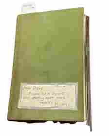 Image of a faded green journal with a rectangular sticker on its front cover. The sticker is dated January of 1981, and is inscribed “Dear Diary, Please leave 3 quarts of milk starting next week. Thanks, Mildred.” The name Mildred is underlined.