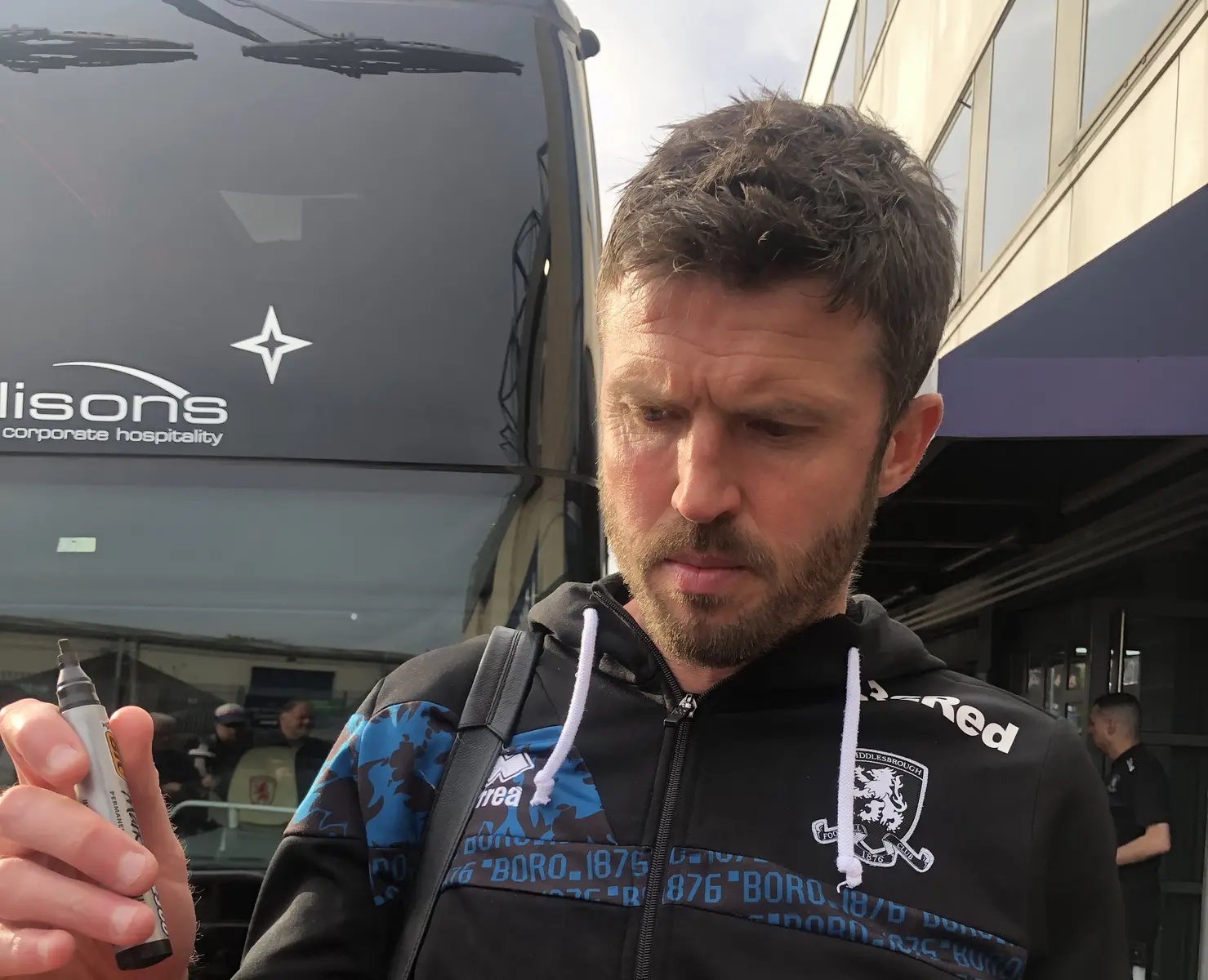 Michael Carrick wearing a Middlesbrough FC hoodie and holding a marker pen.