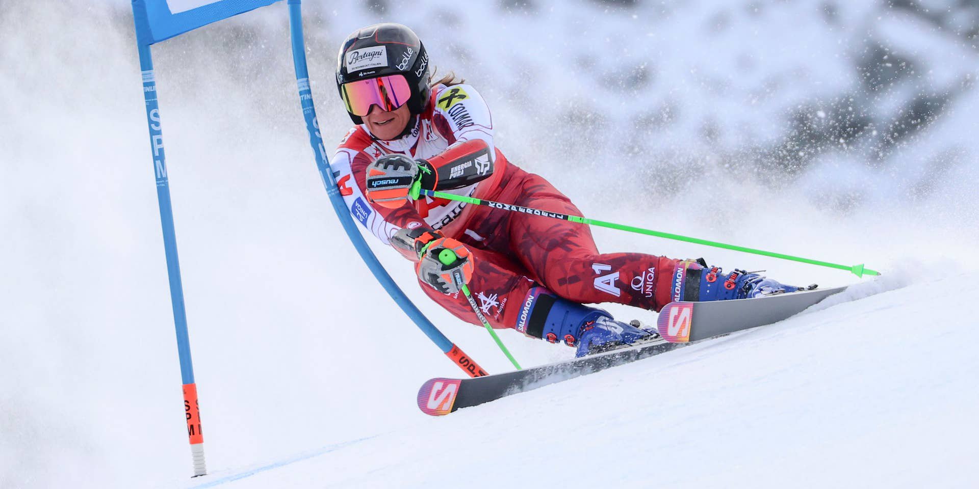 Eine Skirennläuferin fährt beim Riesenslalom mit hoher Geschwindigkeit um ein Tor.