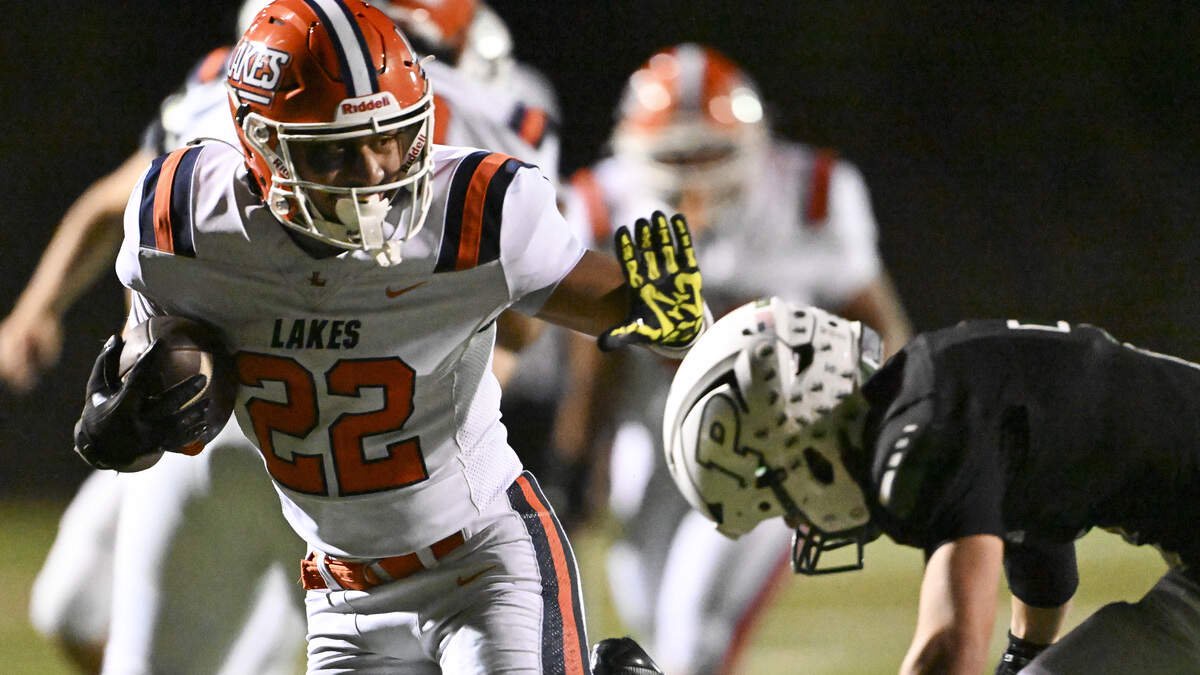 Lakes running back Toetu Moliga (22) carries the ball with pressure from Peninsula defensive back Logan Johnson (2) on Friday, Oct. 23, 2026, at Roy Anderson Field in Gig Harbor, Wash.