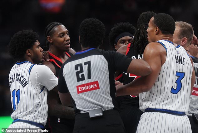 Referee Mitchell Ervin (27) gets between Toronto Raptors' RJ Barrett, second from left, and Orlando Magic's Desmond Bane (3) during the first half of an NBA Cup basketball game in Toronto, Friday, Oct. 30, 2026. (Nathan Denette/The Canadian Press via AP)