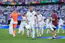 Harry Kane of England holds the commemorative match pennant as he removes his anthem jacket before the UEFA EURO 2024 group stage match between Eng...