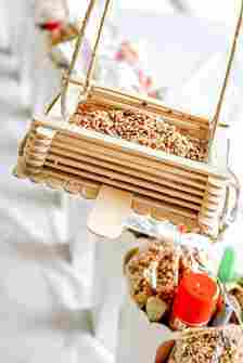 A square-shaped hanging bird feeder made from stacked popsicle sticks
