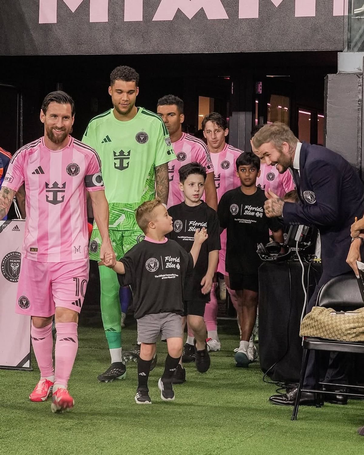 Young boy walks onto football pitch with Lionel Messi