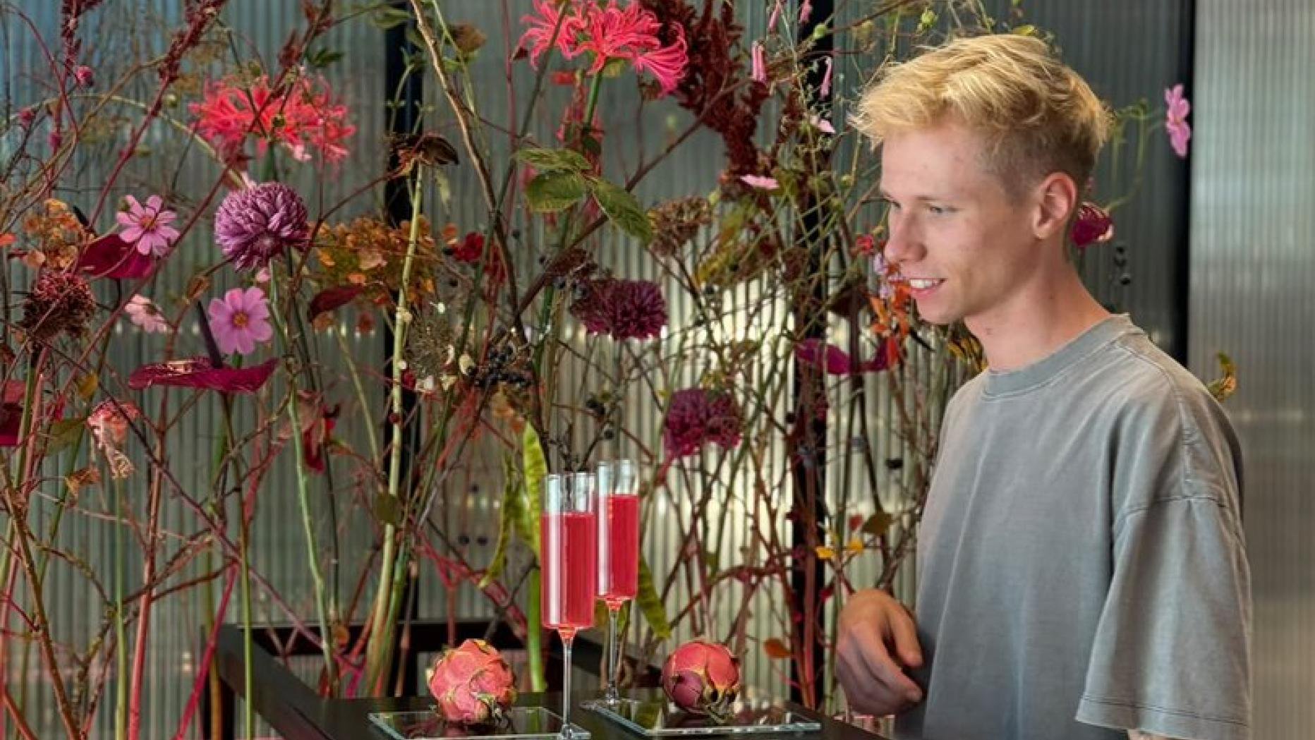 Ein junger Mann steht neben Blumen