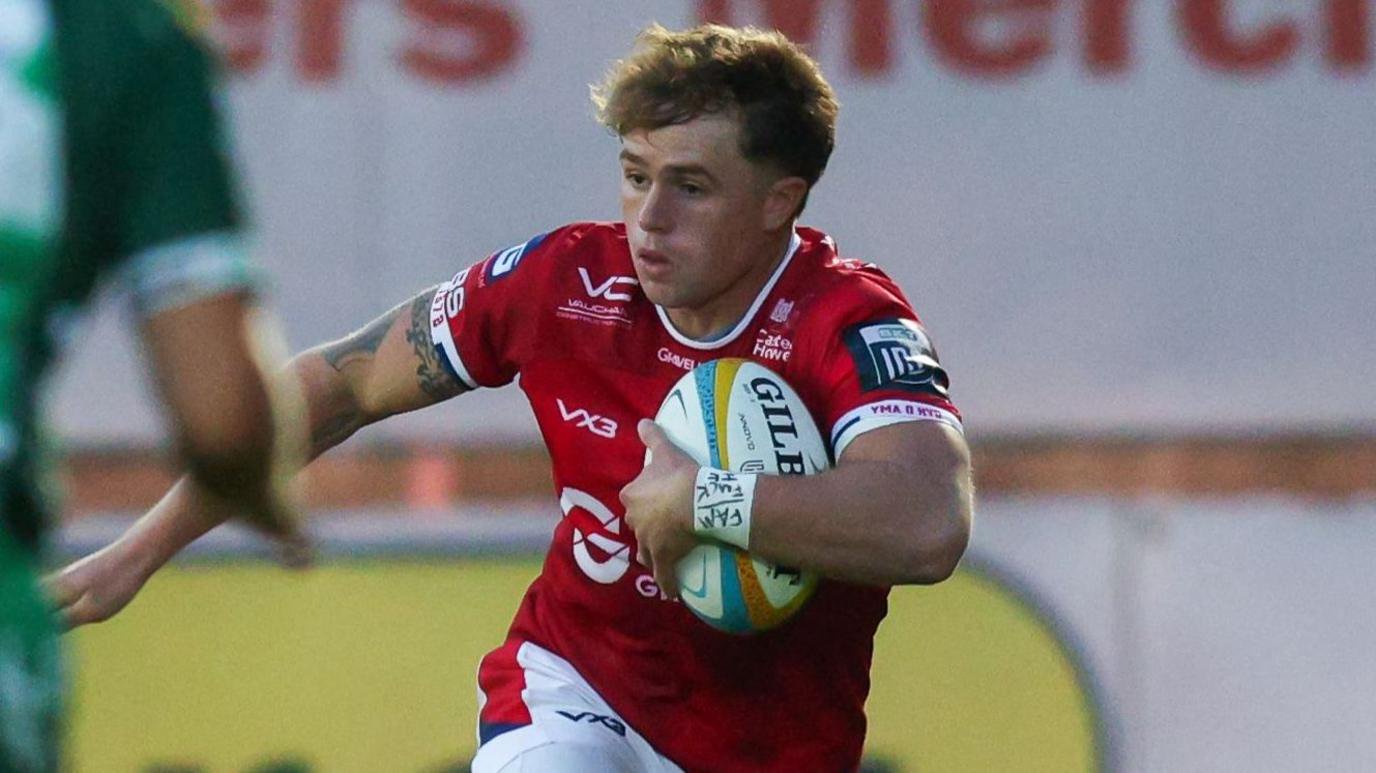 Macs Page runs with the ball under his left arm for Scarlets