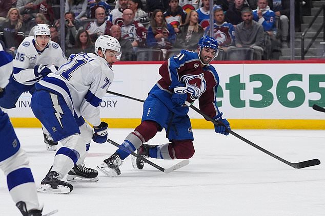 Colorado Avalanche center Nazem Kadri, right, falls as he shoots for a goal as Tampa Bay Lightning center Anthony Cirelli (71) and right wing Ilya Mikheyev (95) defend in the first period of an NHL hockey game Friday, Oct. 23, 2026, in Denver. (AP Photo/David Zalubowski)