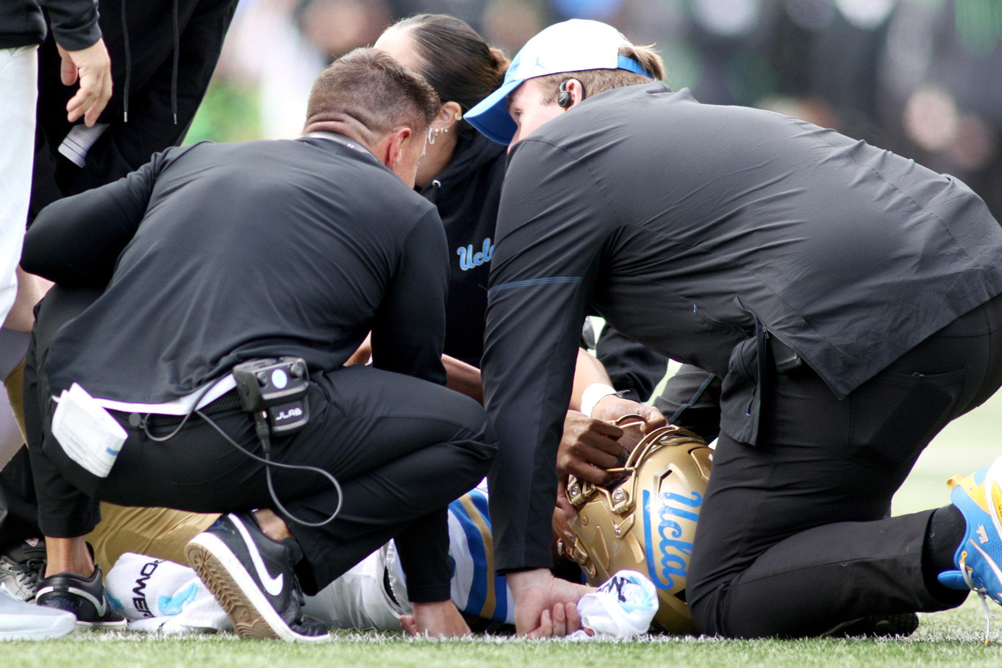 Medical personnel attend to a fallen football player on the field.