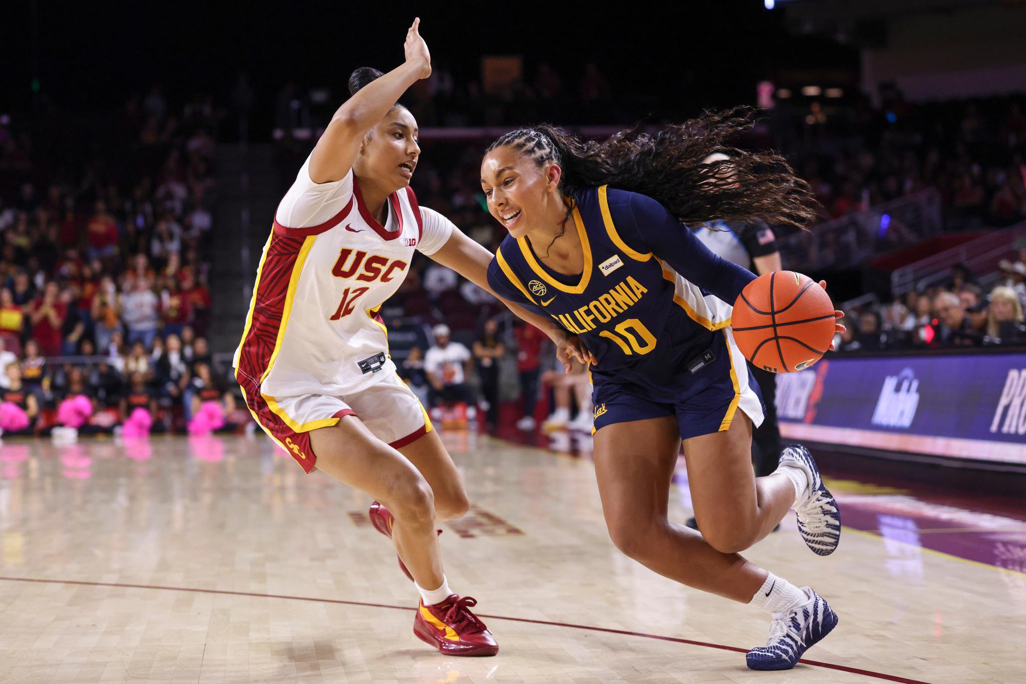 A California basketball player dribbles past a USC defender during a game.