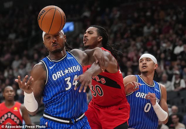 Orlando Magic's Wendell Carter Jr. (34) and Toronto Raptors' Collin Murray-Boyles (30) battle for a loose ball during the first half of an NBA basketball game in Toronto, Wednesday, Oct. 28, 2026. (Nathan Denette/The Canadian Press via AP)