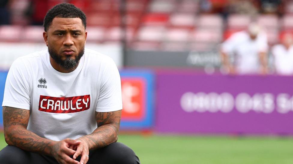 Colin Kazim-Richards looking pensive, wearing a white top with Crawley written on it