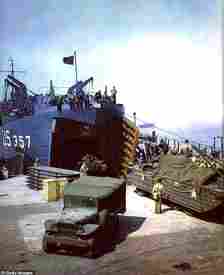 DUKWs, amphibious trucks useful for beach landings (left) and American trucks (right) are loaded on to heavy landing craft ready to sail to France and transport troops in their advance