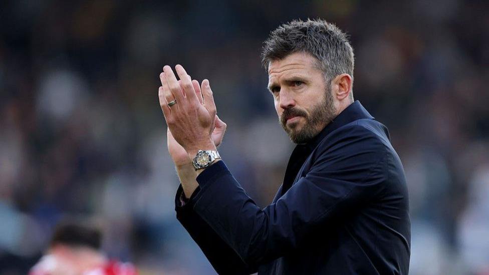 Manchester United head coach Michael Carrick applauding, wearing a dark jacket