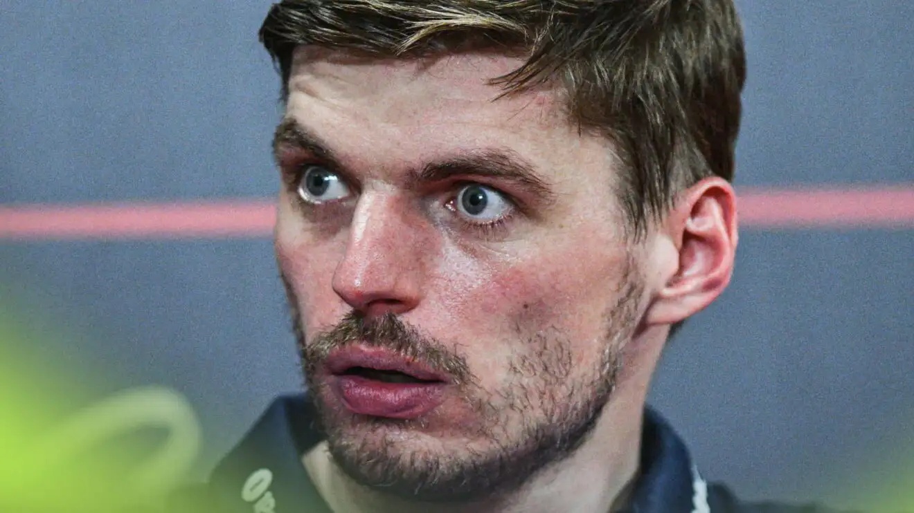 A close-up shot of Max Verstappen with his eyes and mouth wide open in a press conference