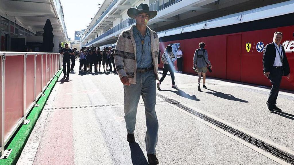 Mercedes driver wearing a cowboy-style outfit, including 10-gallon hat, denim shirt and jeans and cardigan, in the paddock before US Grand Prix first practice