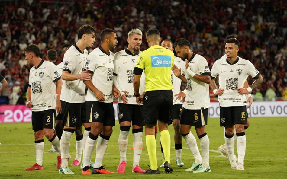 Jogadores do Atlético Mineiro cercam o árbitro no gramado durante a partida.