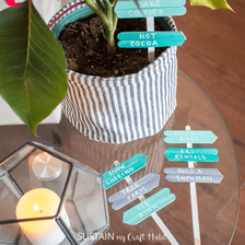 A set of blue and grey miniature popsicle stick signs in and around a houseplant