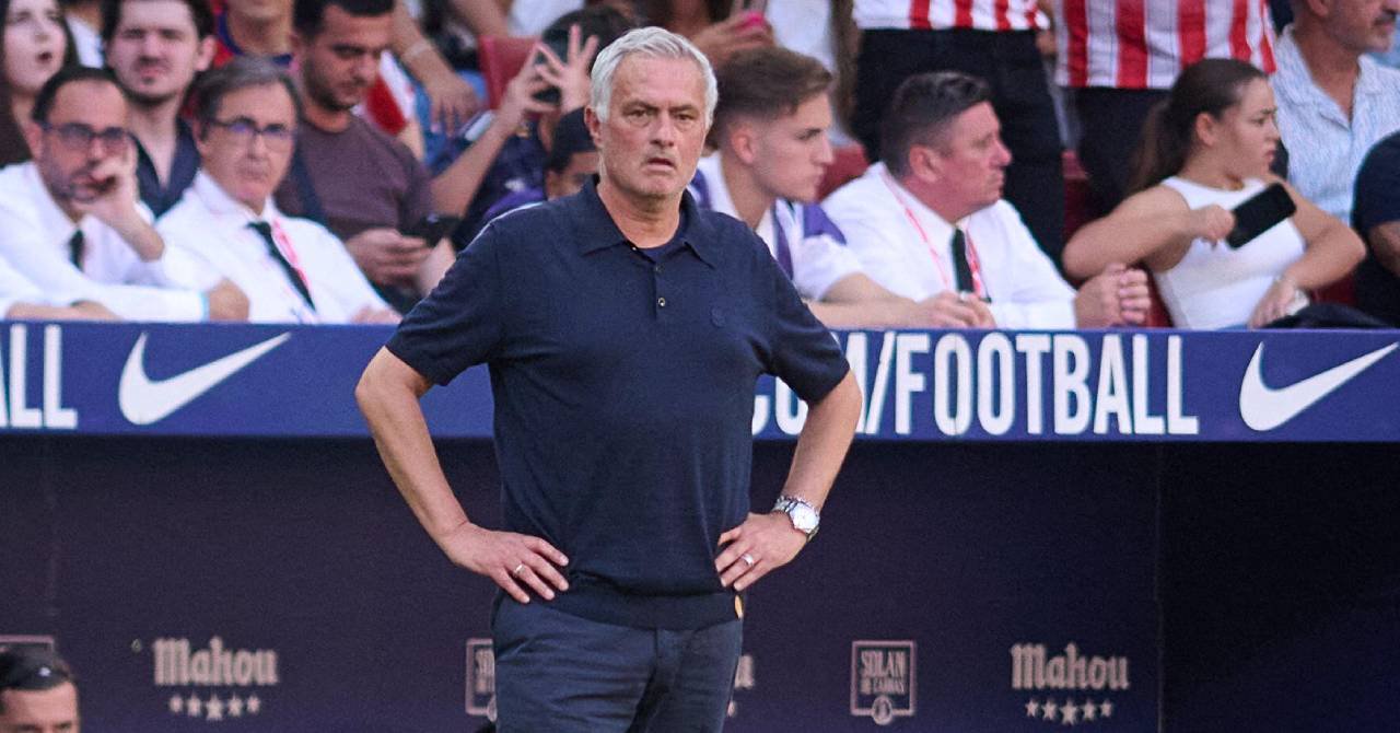 Football manager Jose Mourinho holding his hands on his hips and scowling while wearing a dark blue polo shirt and trousers in a technical area in front of a crowd at Atletico Madrid in his role as Real Madrid Football Club head coach