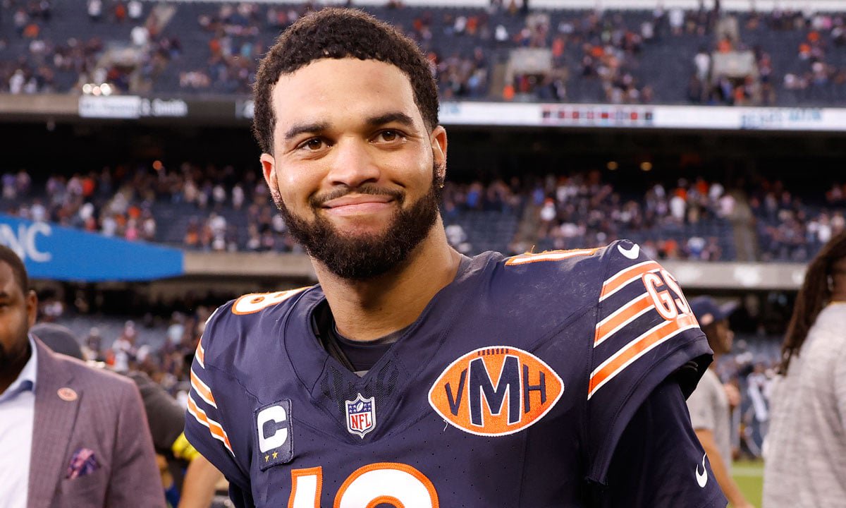 Caleb Williams smiling at a photographer on the NFL field