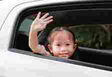 child waving from car