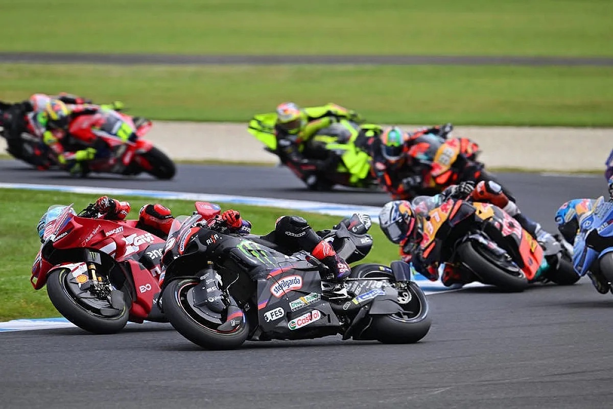 MotoGP riders racing in a tight pack at Phillip Island, including a red Ducati and a black Monster Energy Yamaha leaning into a corner