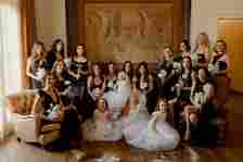 Bride in Wedding Dress and Veil Posing With Bridesmaids in Black Dresses and Flower Girls in White Dresses