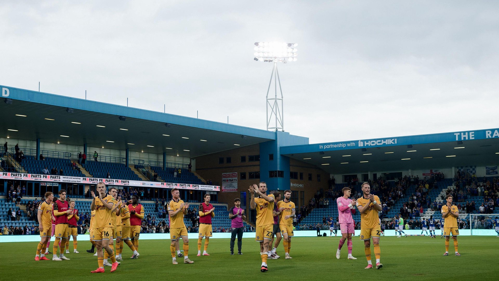 Newport players in all amber applaud travelling fans at Gillingham