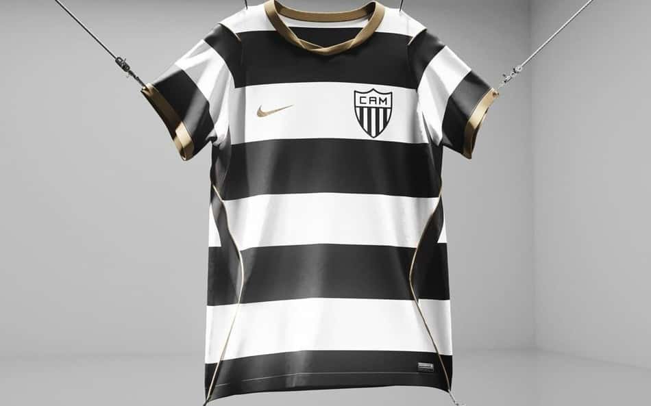 Camiseta do Atlético Mineiro da Nike, listras pretas e brancas com detalhes dourados, suspensa em estúdio.