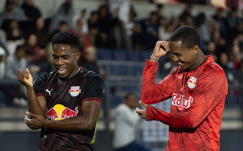 Wallace e Yan, jogadores do Red Bull, celebram durante partida de futebol em estádio.