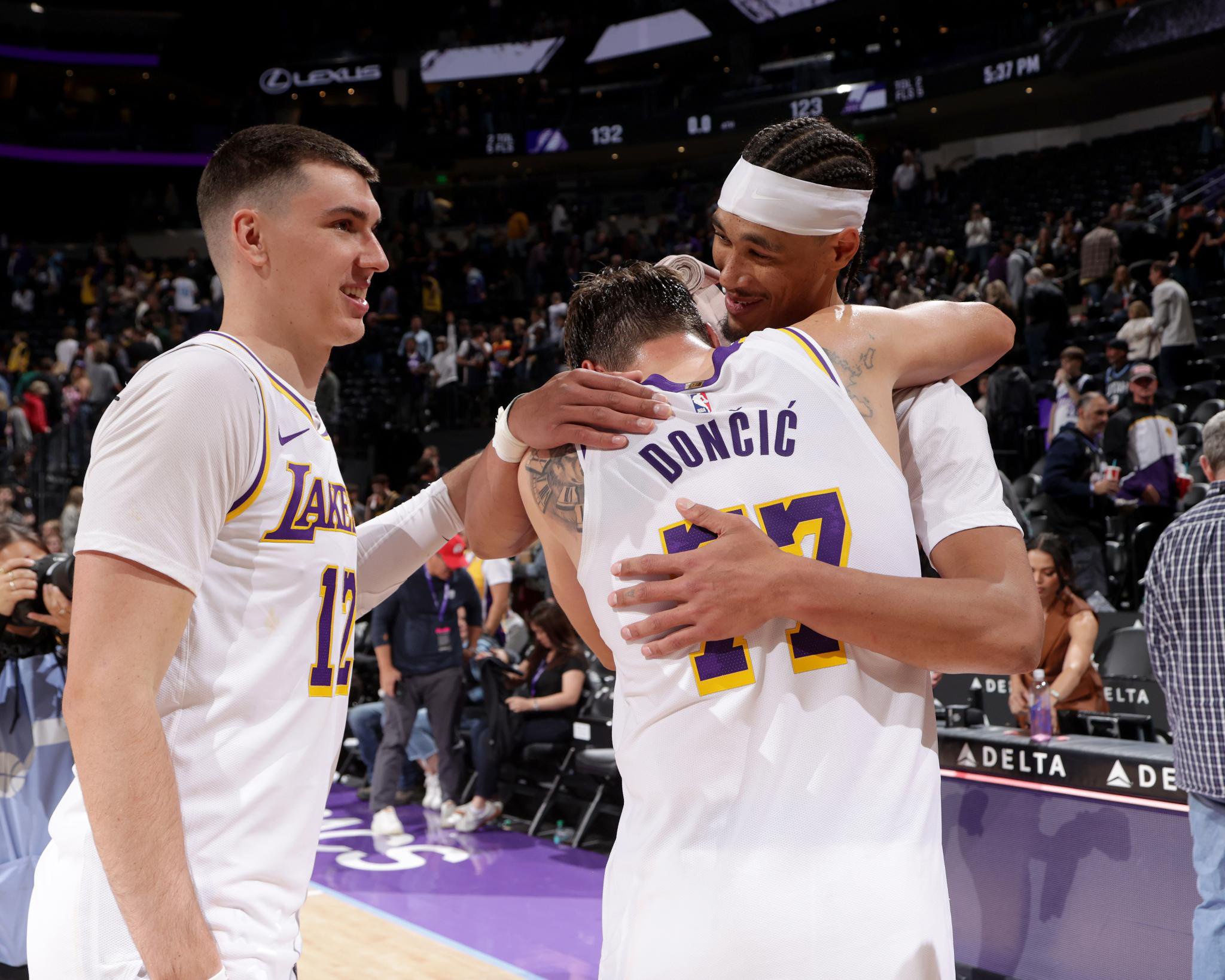 Luka Doncic, Jake LaRavia, and Jaxson Hayes embrace on the court after a game.