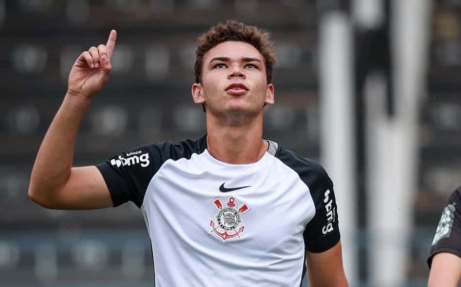 Miguel Moscardo aponta para o alto durante a partida, vestindo camisa branca com detalhes pretos e emblema no peito.
