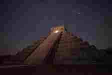 The Great Pyramid beneath a starry sky, the upper chamber illuminated with golden light.