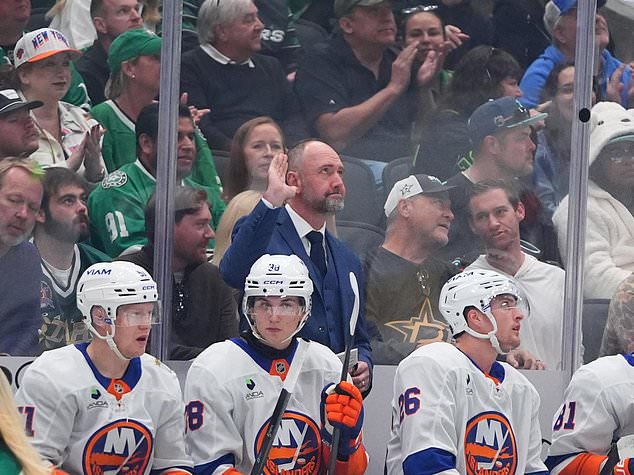 New York Islanders head coach Peter DeBoer, center, waves from behind the bench after being acknowledged during the first period of an NHL hockey game against the Dallas Stars, Sunday, Oct. 25, 2026, in Dallas. (AP Photo/LM Otero)