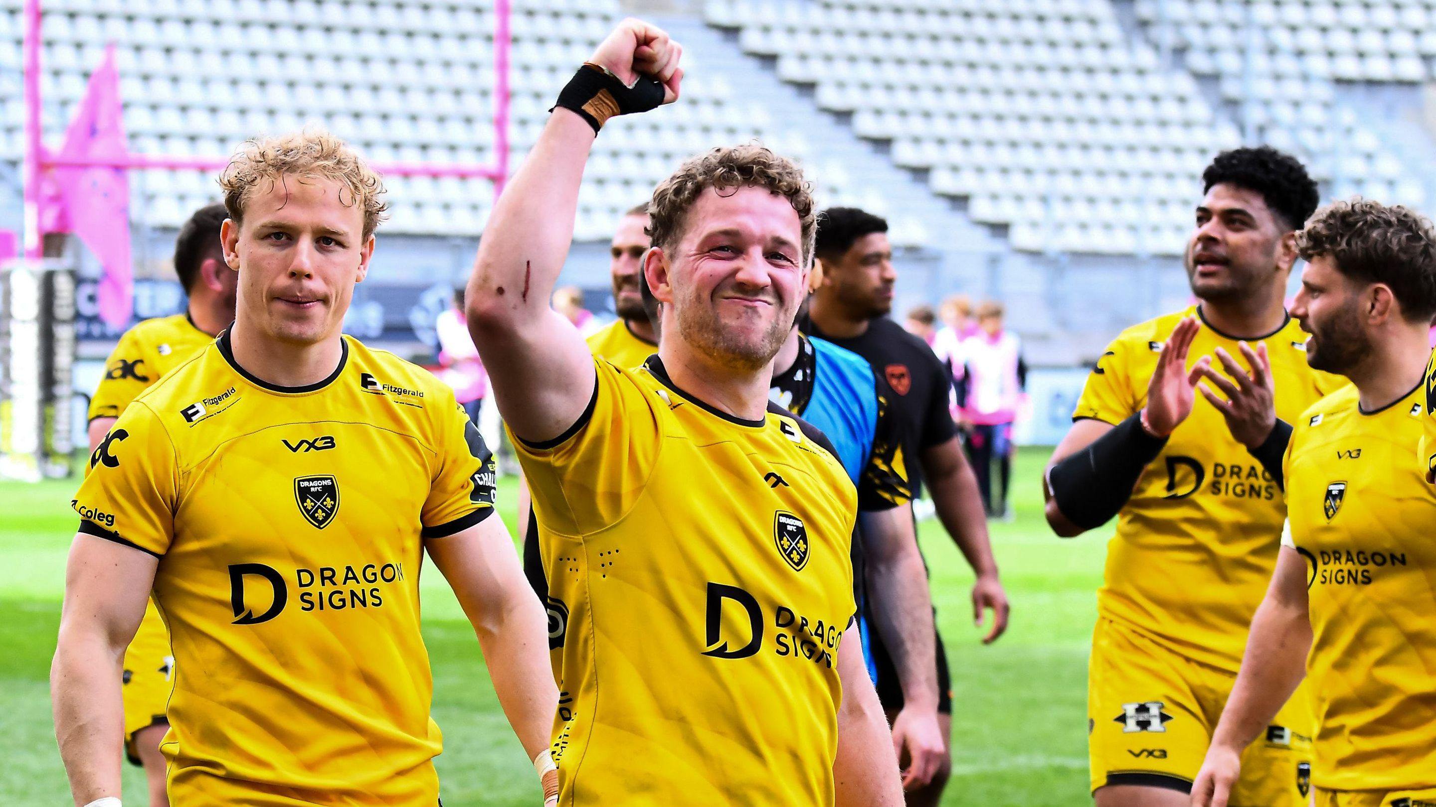 Angus O'Brien clenches a raised fist as Dragons players in amber celebrate
