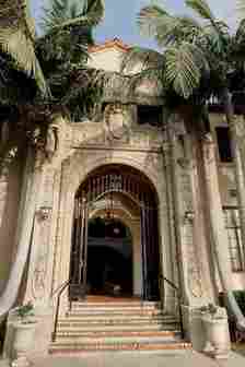 Front of Venue with Black Iron Gate in Doorway and Palm Trees 