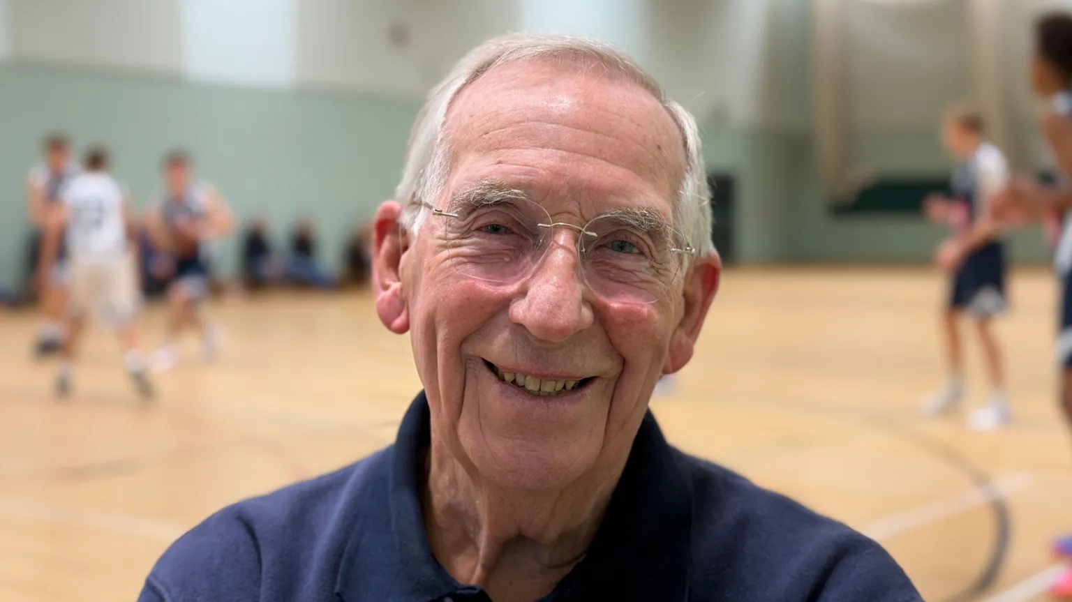 BBC Photo of Paul in glasses in a blue shirt on a basketball court. 