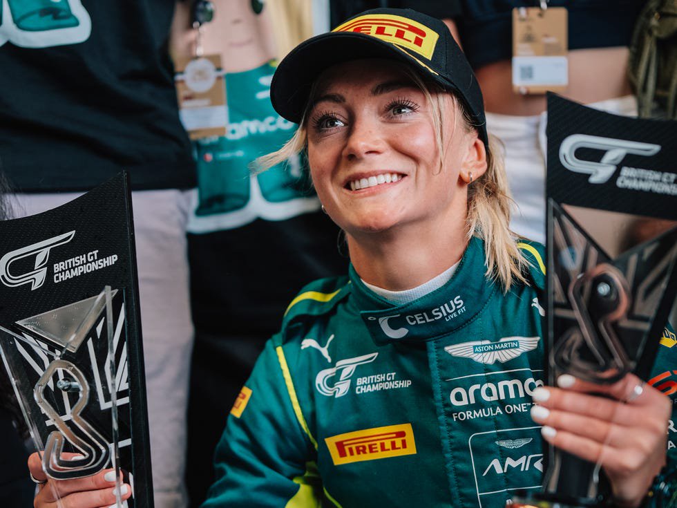 racing driver in green suit smiling with british gt championship trophy.