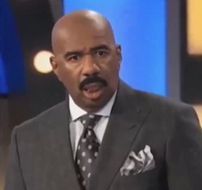 A surprised Steve Harvey wearing a suit and tie