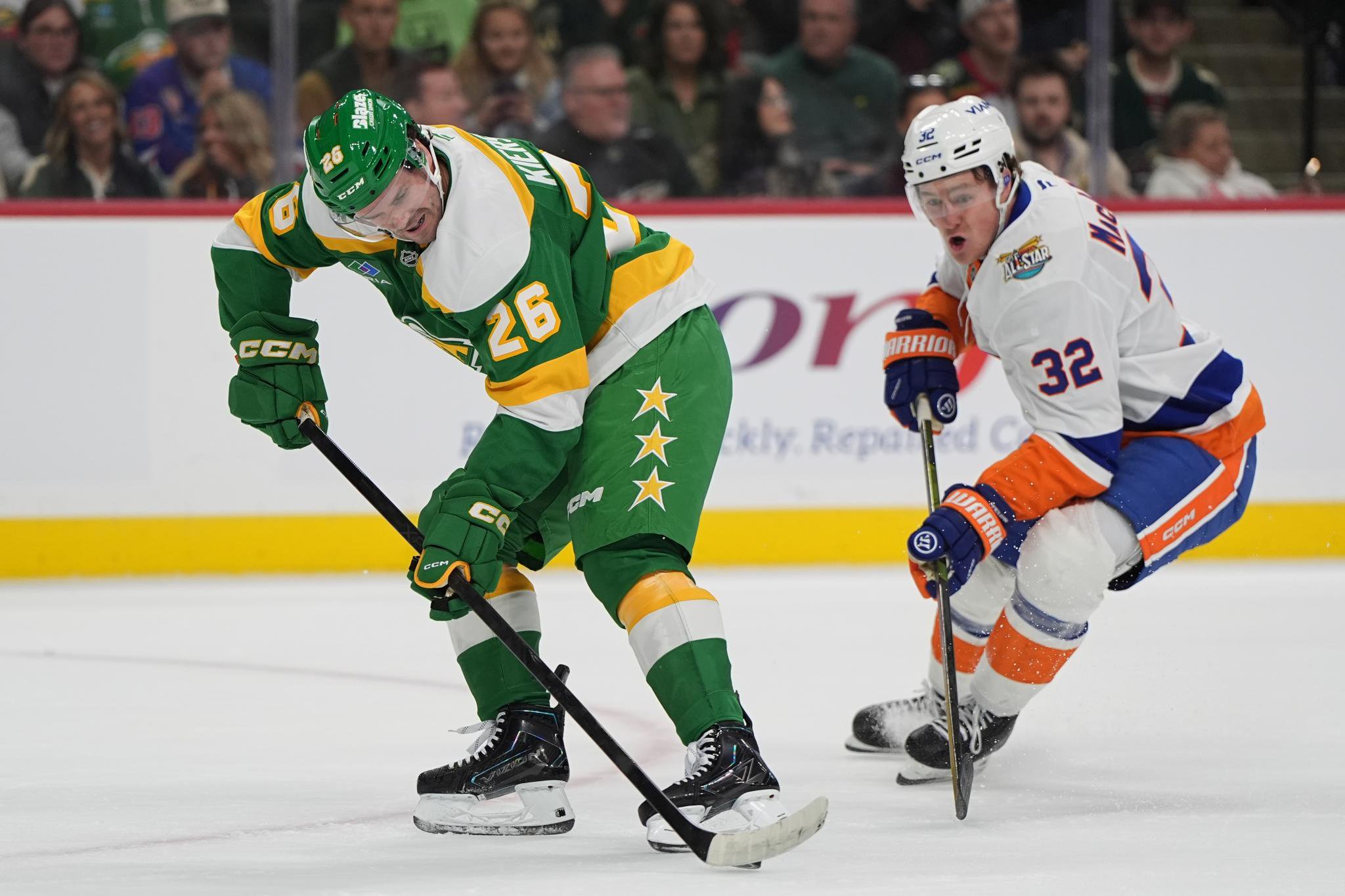 Minnesota Wild defenseman Matt Kiersted skates with the puck as New York Islanders center Kyle MacLean defends.